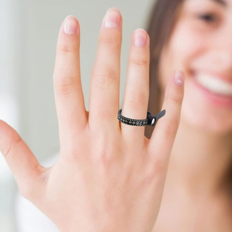 Schwarzes Ringmaß am Finger einer Frau, die im Hintergrund lächelt