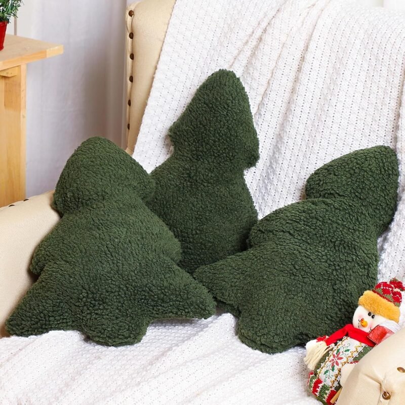 Drei grüne Christbaumkissen auf einem Sessel mit einer weißen Strickdecke