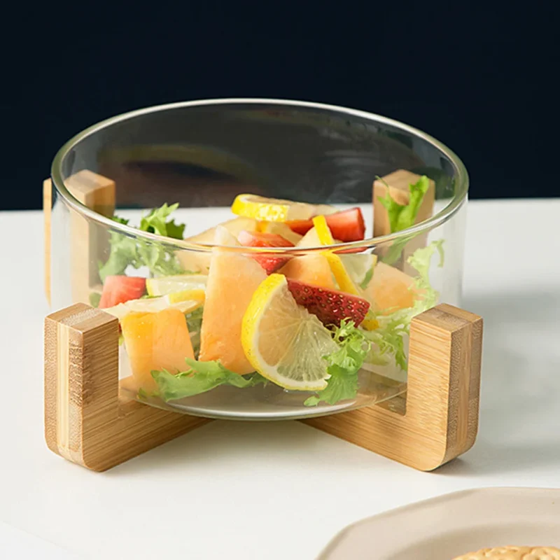 Glasschüssel auf einem Holzständer mit Obstsalat auf einem Esstisch