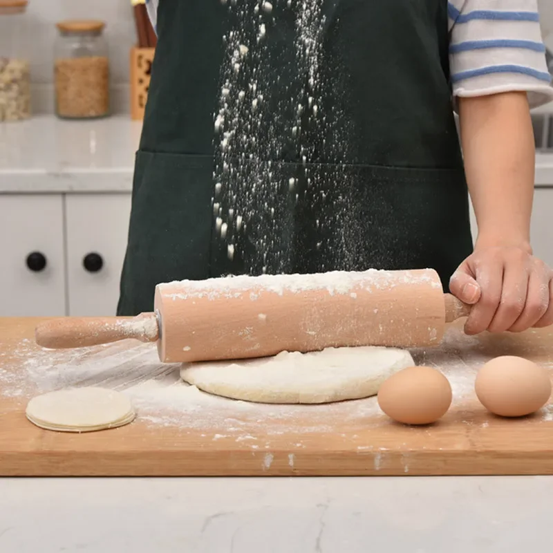 Nudelholz aus Buche rollt bemehlten Teig auf einem Holzbrett in einer Küche aus