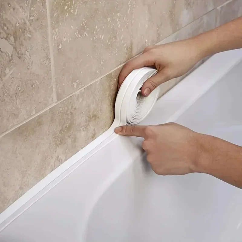 Weißes Dichtband wird entlang der Fuge zwischen Badewanne und gefliester Wand aufgebracht