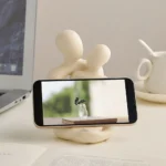 Abstrakte Paarskulptur aus Kunstharz auf einem Schreibtisch mit Smartphone, Vorderansicht