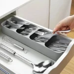 Schmaler grauer Besteckkasten mit Besteck in einer offenen Küchenlade, Hand nimmt eine Gabel