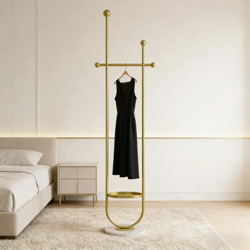 Goldene freistehende Garderobe mit Marmorfuß und einem schwarzen Kleid in einem hellen Schlafzimmer