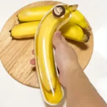 Durchsichtige Bananenbox mit Affendeckel über Bananen auf einem Holzbrett