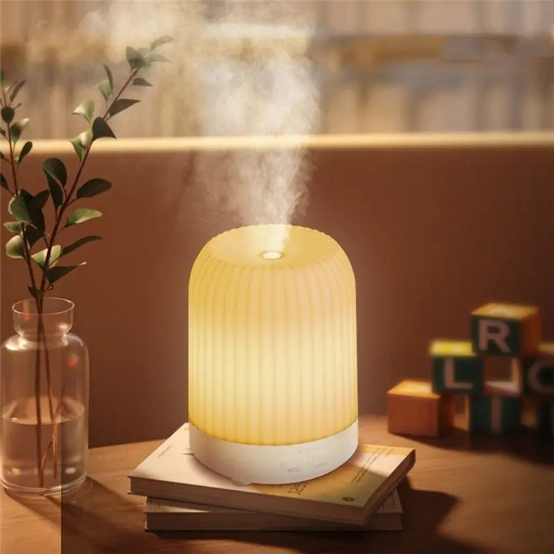 Leuchtender Aroma-Diffusor verströmt Nebel auf einem Bücherstapel neben einer Vase